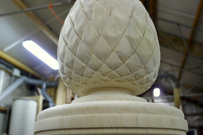 Handgesneden dennenappel in Yellow Poplar voor de bekroning van de trappaal.
