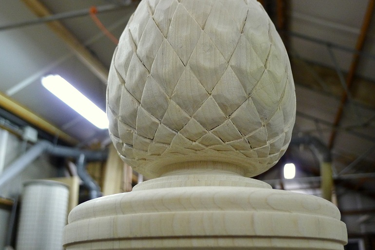 Handgesneden dennenappel in Yellow Poplar voor de bekroning van de trappaal.